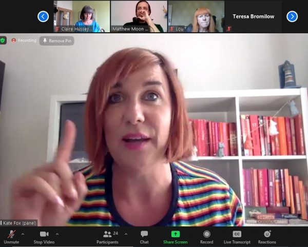 Screenshot from the online event of Kate, a white woman with short pink hair, wearing a stripy, multicoloured long sleeved top.