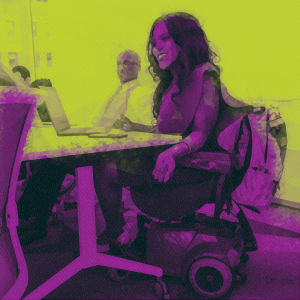 Recruiting Disability History Month. An image of a female wheelchair user. She is wearing a red dress and is chairing a meeting.
