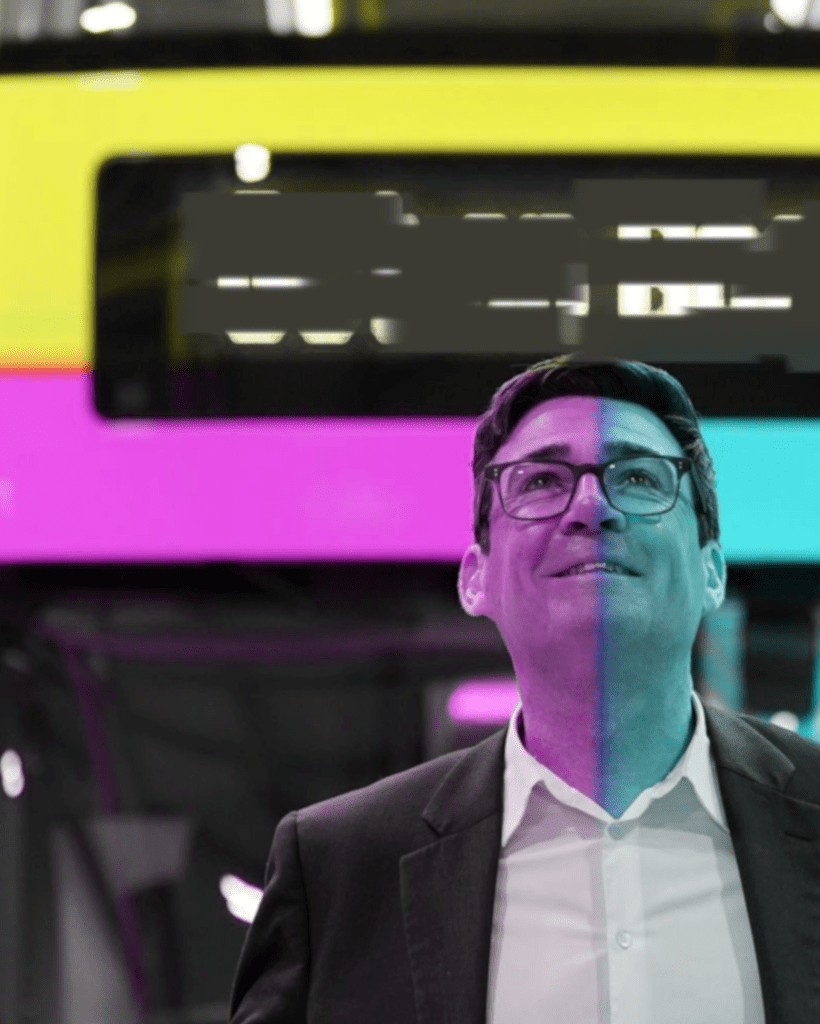 Andy Burnham Free Bus Pass: Close-up photo of Andy Burnham looking upward and smiling slightly, standing inside a Manchester Metrolink tram, with half his face tinted teal and half tinted magenta, against a yellow, magenta, and cyan colour-blocked background.